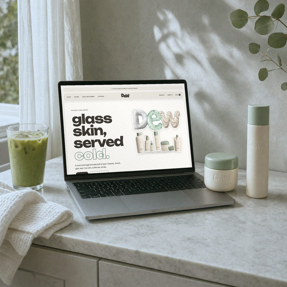 Dew World homepage on a laptop on a marble vanity with Water Cream and Hydrating Essence